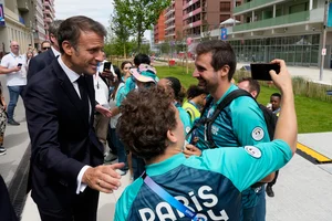 AP : French President Emmanuel Macron poses for a selfie with volunteers as he visits the Olympic Village, at the 2024 Summer Olympics, Monday, July 22, 2024, in Paris, France.