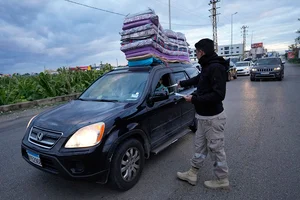 | Photo: AP/Hussein Malla : Israel Lebanon Ceasefire: A Civil Defense worker distributes safety fliers to people