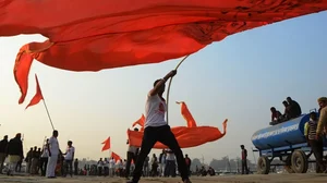 Indian Hindu devotees host religious saffron flag during a royal religious procession at sangam, confluence of Ganga, Yamuna, and mythological Saraswati river in Prayagraj, Uttar Pradesh.