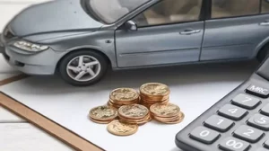 Car model, calculator and coins on white table