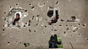 Palestinian children play around a damaged house in Gaza City