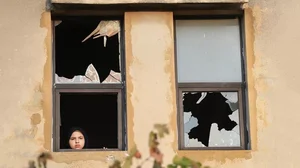 End of Innocence: A Lebanese girl looks through a shattered glass window after Israeli shelling landed near her house in Dahaira village, South Lebanon