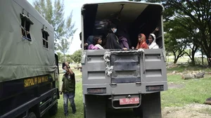 Rohingya women and children sit on the back of a truck as they are being transferred to a temporary shelter, in Banda Aceh, Aceh province, Indonesia.