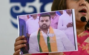 Getty Images : Congress spokesperson Supriya Shrinate shows a photograph featuring Prajwal Revanna at a press conference in Bengaluru on May 1, 2024 | 