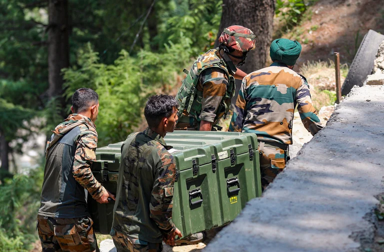 Army personnel carry weapons and equipment near the encounter site, in Desa village of Doda district - PTI