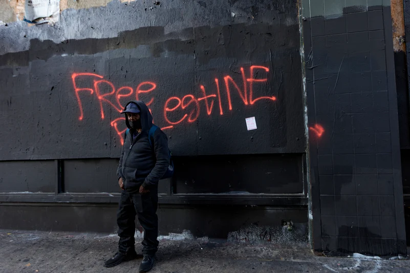  A man stands in front of Free Palestine graffiti 