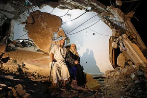 | Photos: Q. Sakamaki : A Home That Was: Ayman Abu Reida (44) and his wife Myrebert (36) stand outside their destroyed home in Khan Yunis. The couple continues to stay in the dilapidated house as there is no other option