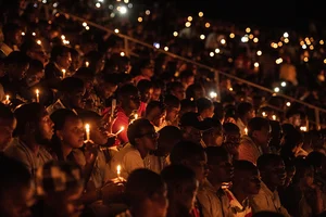 via Getty Images : People hold candles during a commemoration ceremony of the 1994 genocide on April 07, 2019 at Amahoro Stadium in Kigali, Rwanda.