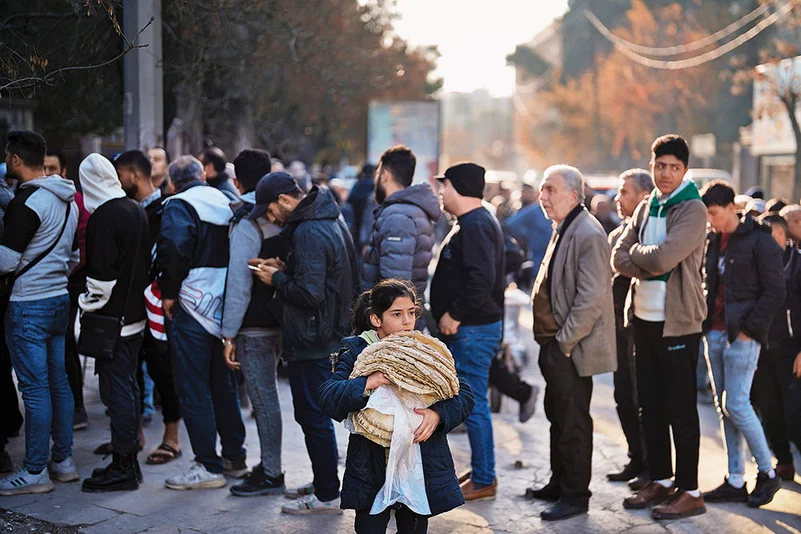 Daily Travails: Residents stand in line to buy bread from a bakery in Aleppo, Syria