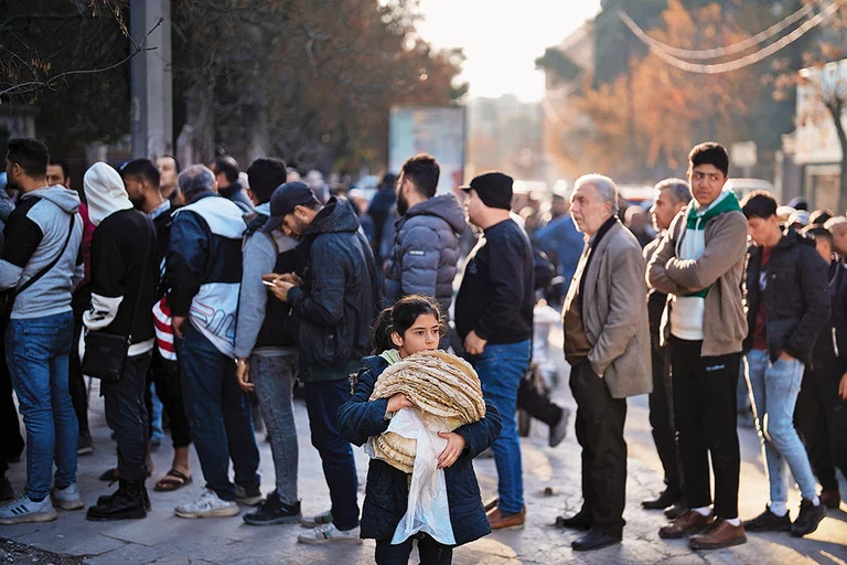 Daily Travails: Residents stand in line to buy bread from a bakery in Aleppo, Syria - Photo: AP