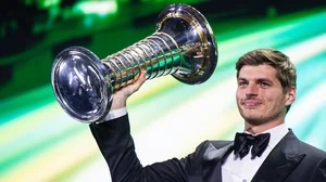 Max Verstappen holds aloft the world championship trophy at the FIA awards in Rwanda.