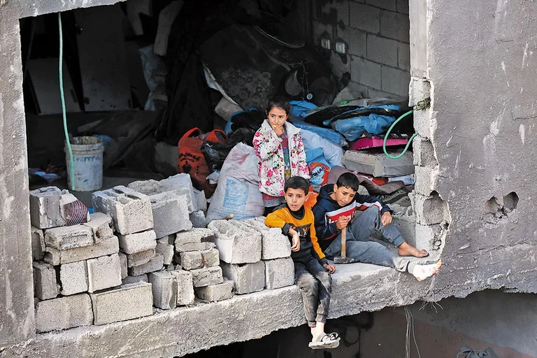 Children look on as civil defence teams conduct rescue operations following an Israeli attack in Gaza - Getty Images