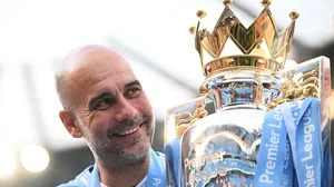 Pep Guardiola poses with the Premier League trophy.