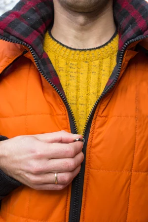 Shutterstock : A person buttons up a winter jacket