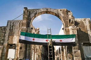 | Photo: AP : War and Life: A worker sets up a Syrian “revolutionary” flag at the entrance of a mosque in Damascus