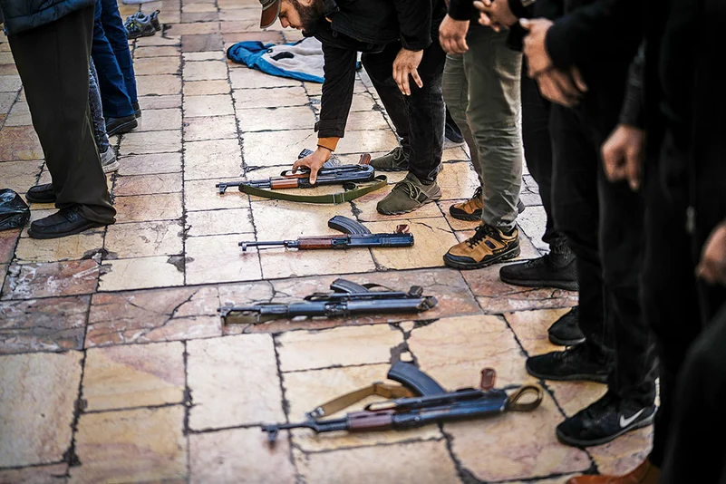 Syrian fighters place their weapons on the floor before Friday prayers